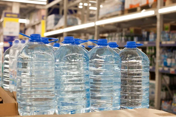 Plastic bottles with blue caps with clean drinking water in a supermarket. Packed in plastic wrap