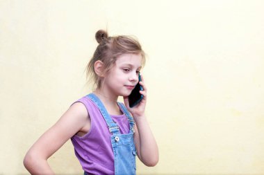 Sarışın kız. 8 yaşında. Telefona cevap veriyor.