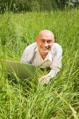 Genç iş adamları dışarıda gri dizüstü bilgisayarlarıyla rahatlıyorlar.