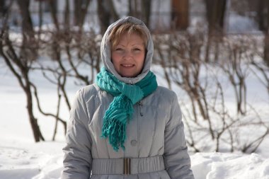 Açık havada kalın ceketli, gülümseyen olgun kadın.
