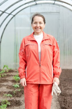 Turuncu eşofmanlı kadın serada.