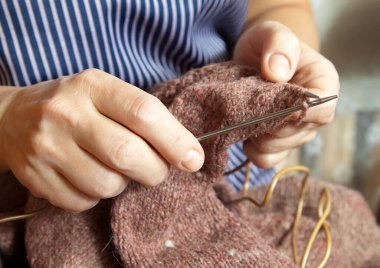  Kadın elleri yün ve metal örgü iğnesiyle örüyordu.