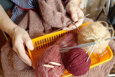 Kadın elleri yün ve metal örgü iğnesiyle