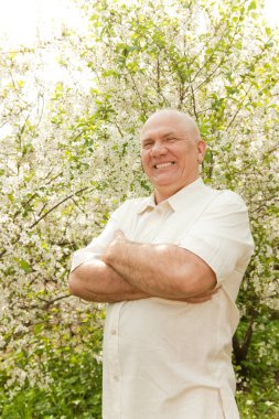 Bahçedeki beyaz saçlı orta yaşlı adamın portresi.