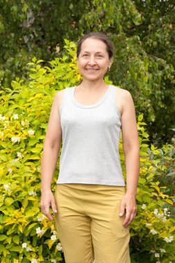 Bahçesinde yasemin olan gülümseyen yetişkin bir kadın.