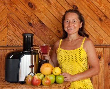 Mutfaktaki kadın taze sıkılmış meyve suyu yapıyor.