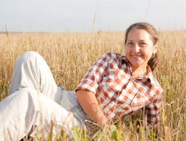 Yaz manzarasına gülümseyen olgun bir kadın.