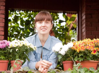  Balkonda çiçekli genç bir kadın.