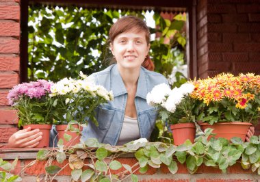 Çiçeklerle dolu bir kır evinin verandasında güzel bir kız
