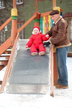 Bebek babasıyla oyun parkında kayıyor.