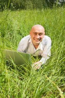 Genç iş adamları dışarıda gri dizüstü bilgisayarlarıyla rahatlıyorlar.