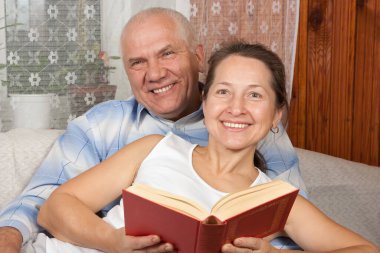 İçerde kitap okuyan mutlu bir çiftin portresi.