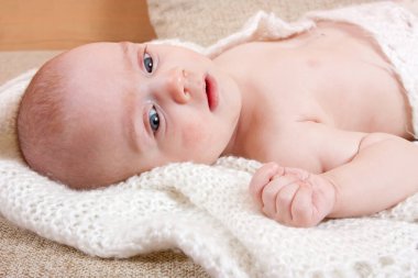 Tatlı bebek beyaz şalla kanepede dinleniyor.