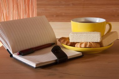 Tahta arka planda buharlı bir fincan sıcak çay. Hafif ton.