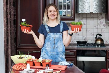 Mutfakta kot tulumlu genç bir kadın otlarla ilgileniyor.