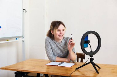 16 yaşındaki bir kız akıllı telefondan video kaydediyor ve kendini lambayla ışıklandırıyor.