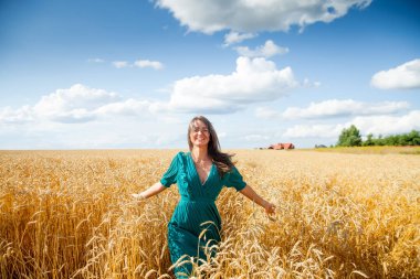 Girl in   dress walking through   field of wheat