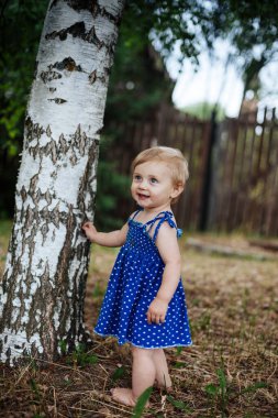 Huş ağacında çıplak ayakla bir yaşındaki bir bebeğin portresi.