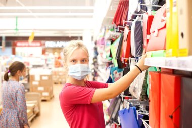 Tıp maskesiyle ofis malzemesi seçen genç kız öğrencinin portresi.