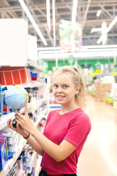 Student girl in   supermarket near   department with   office supplies