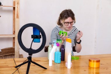 Güzel genç kız telefonunda kozmetik konulu video kaydediyor.