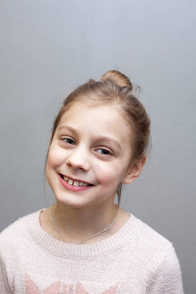 Portrait of   eight-year-old girl on   gray background. 