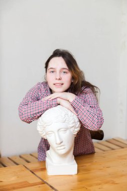 Genç bir kız, genç bir kızın alçı başıyla poz verir.