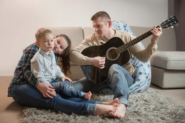 Pai feliz e família tocando guitarras em casa — Fotografia de Stock