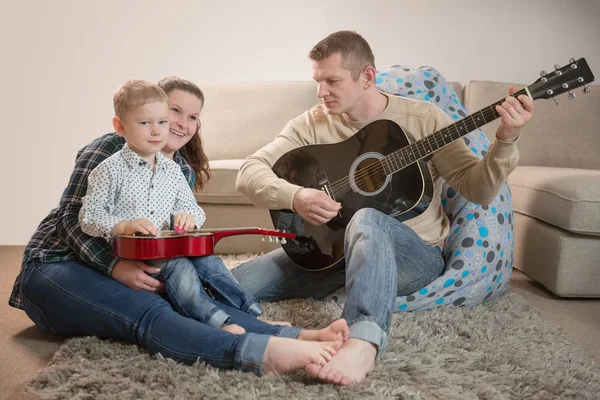 Padre feliz y familia tocando guitarras en casa — Foto de Stock