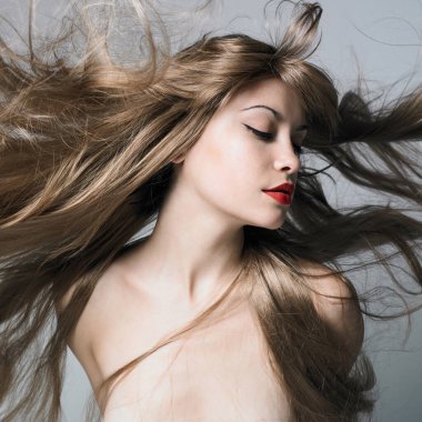 Mavi arka planda oturan zarif, güzel bayan. Sarışın, genç ve seksi bir manken. Güzel bir kadın fotoğraf stüdyosunda çıplak poz veriyor..