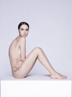 Kısa saçlı güzel esmerin sanat stüdyosu portresi. Beyaz stüdyoda çıplak vücutlu genç ve seksi bir model. Klasik profesyonel makyajlı çıplak kadın. 