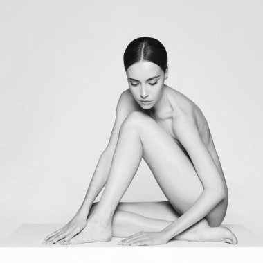 Kısa saçlı güzel esmerin sanat stüdyosu portresi. Beyaz stüdyoda çıplak vücutlu genç ve seksi bir model. Klasik profesyonel makyajlı çıplak kadın. 