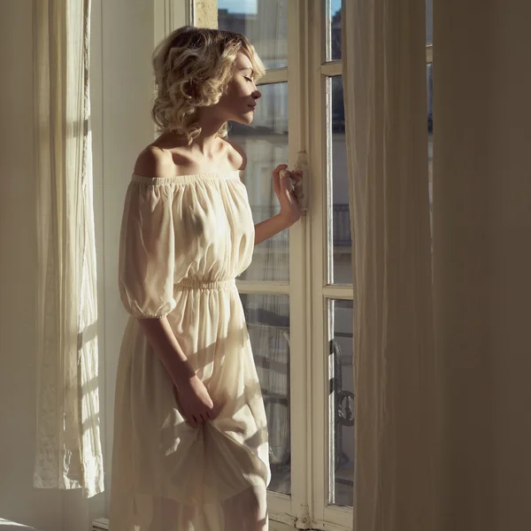 Mooie blonde bij het venster — Stockfoto