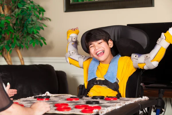 Young disabled boy in wheelchair playing checkers — Stock Photo, Image