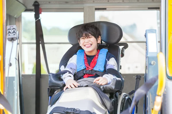 Smiling disabled boy in wheelchair on yellow school bus lift — Stock Photo, Image