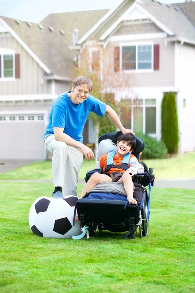 Père jouant au soccer avec son fils handicapé en fauteuil roulant au parc — Photo