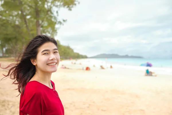 笑顔Biracialアジアの白人ティーン女の子に熱帯のビーチ見ますに向かってアクアブルー海オン曇りの日 — ストック写真