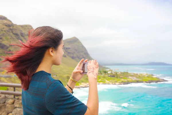在夏威夷瓦胡岛的热带夏威夷海景和绿山之上 站着一位年少的女孩 她用智能手机拍照 — 图库照片