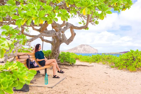 ハワイ州オアフ島のMakapu Uビーチのベンチでリラックスした10代の女の子 青い海の景色を望む暗い木陰の下で — ストック写真