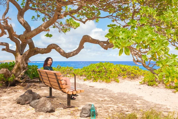 ハワイ州オアフ島のMakapu Uビーチのベンチでリラックスした10代の女の子 青い海の景色を望む暗い木陰の下で — ストック写真