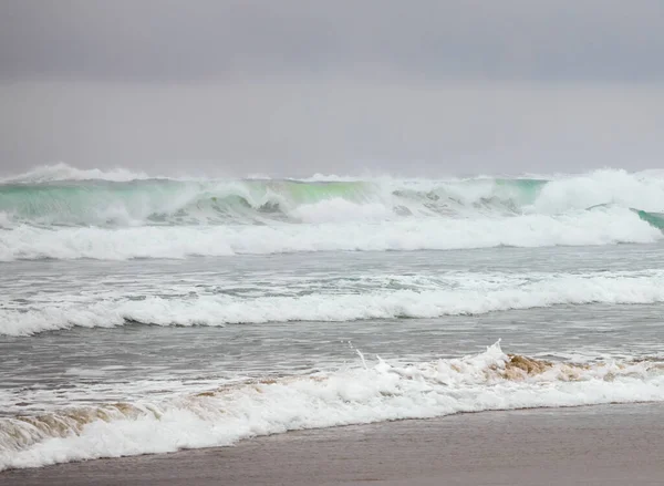 夕暮れ近くの霧深い日に太平洋の美しいエメラルドグリーンの波がショーを打つ — ストック写真