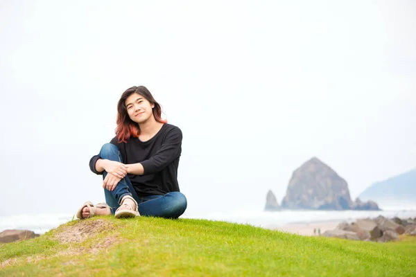 在多雾的日子里 太平洋西北部的海洋边 一个年少的少女坐在长满青草的小丘或山坡上 — 图库照片