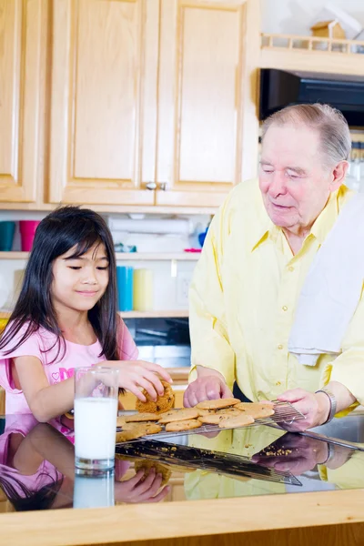 Elderly man sharing cookies with granddaughter — Stock Photo, Image