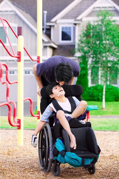 Garçon handicapé en fauteuil roulant avec grand frère au parc — Photo