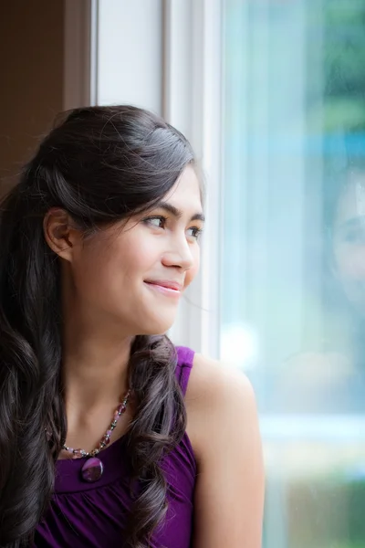 Hermosa mujer joven biracial sonriendo por la ventana — Foto de Stock