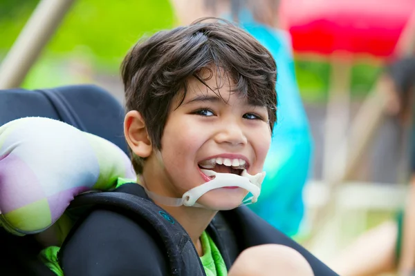 Handicap acht-jarige jongen in rolstoel glimlachen — Stockfoto