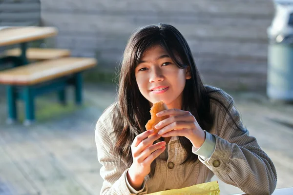 Giovane ragazza adolescente biraciale all'aperto mangiare hamburger — Foto Stock