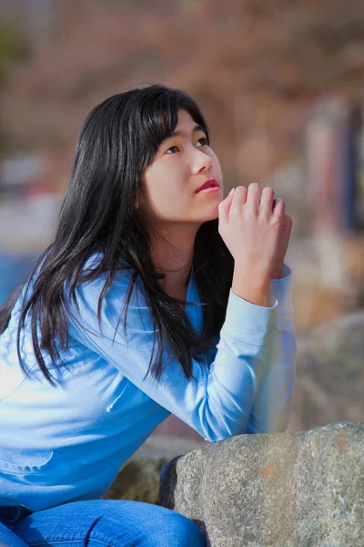 Junges Teenie-Mädchen sitzt draußen auf Felsen und betet — Stockfoto