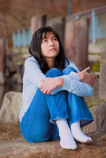 Trauriges Teenie-Mädchen sitzt auf Felsen am Ufer des Sees, einsam, expressi — Stockfoto