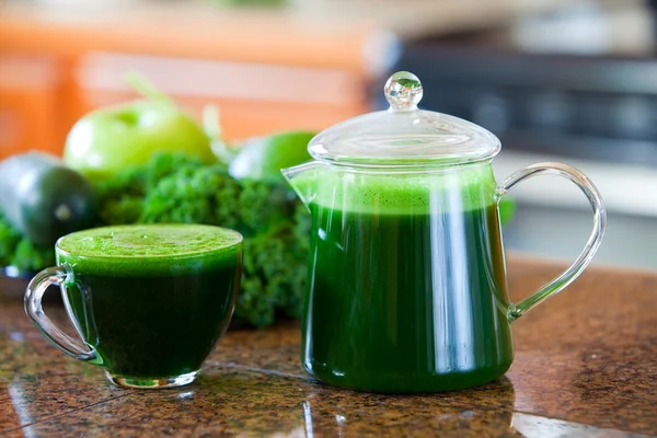 Glass cup of green vegetable juice on kitchen counter — Stock Photo, Image